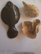 Aino Töyryn tekemä maalattu kipsikala ja Eeva Töyryn tekemä keramiikkasiili ja kukka.